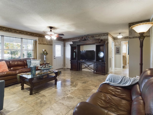 living room featuring ceiling fan and a textured ceiling