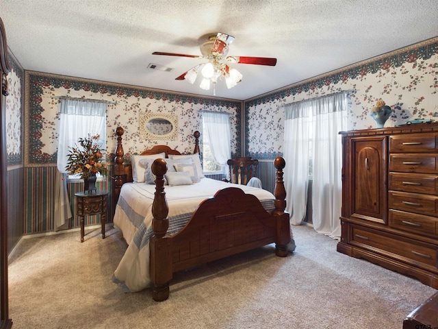 bedroom featuring light carpet, a textured ceiling, and ceiling fan