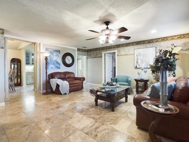 living room featuring a textured ceiling, ornate columns, and ceiling fan