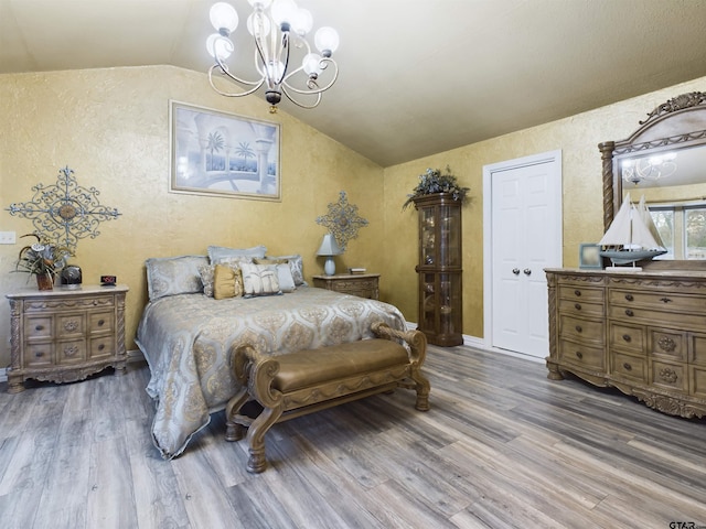 bedroom featuring a chandelier, hardwood / wood-style flooring, and lofted ceiling