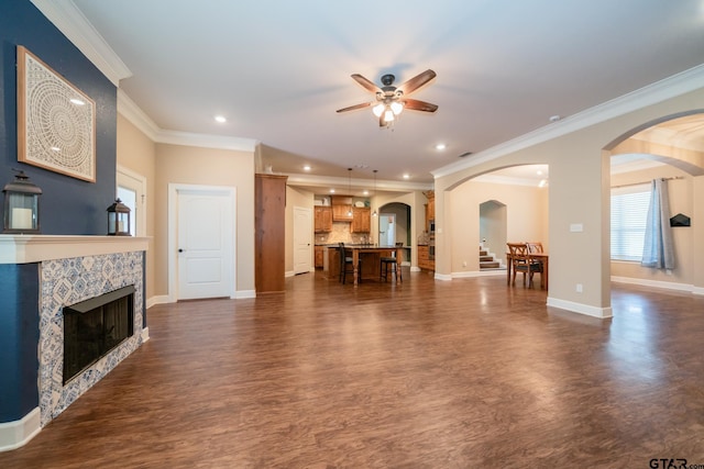 living room with dark wood-style floors, recessed lighting, ornamental molding, a tile fireplace, and baseboards