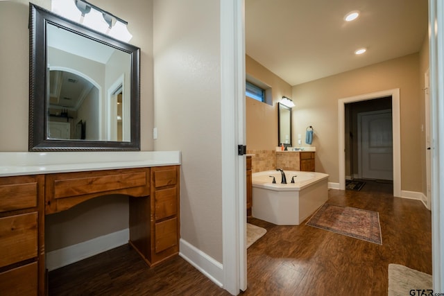 full bathroom with a garden tub, vanity, baseboards, and wood finished floors