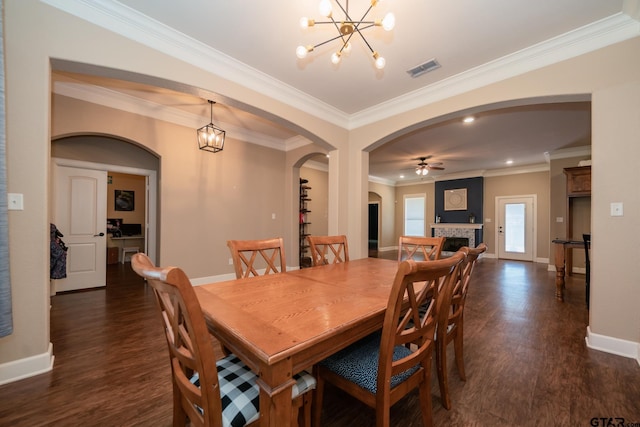 dining space featuring arched walkways, a fireplace, dark wood-style floors, and baseboards