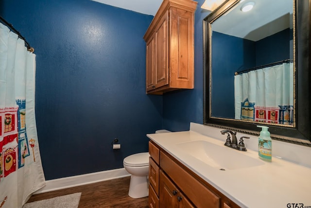 bathroom with vanity, wood finished floors, toilet, and baseboards