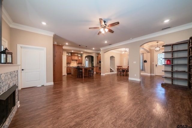 living area featuring arched walkways, dark wood-style flooring, a fireplace, and visible vents