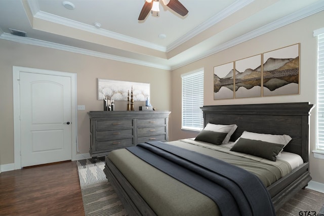 bedroom with baseboards, a tray ceiling, dark wood-type flooring, and crown molding