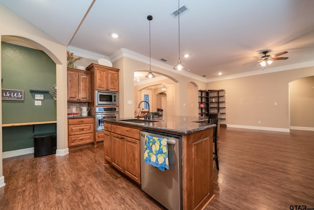 kitchen featuring stainless steel appliances, a sink, visible vents, brown cabinets, and a center island with sink