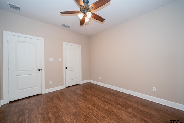 spare room with a ceiling fan, baseboards, visible vents, and dark wood-style flooring