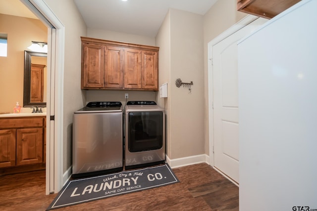 laundry area with dark wood-style flooring, a sink, baseboards, washer and dryer, and cabinet space