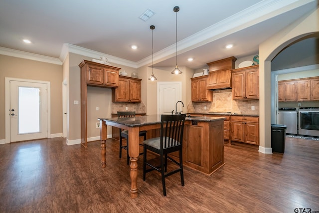 kitchen with visible vents, dark wood-style floors, custom range hood, brown cabinets, and washing machine and clothes dryer