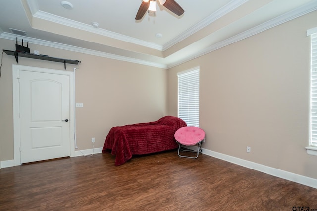 bedroom with a tray ceiling, crown molding, a ceiling fan, wood finished floors, and baseboards