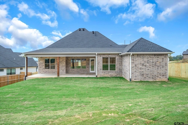 back of property with a yard and a patio area