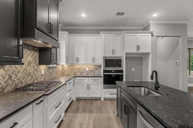 kitchen with white cabinets, sink, dark stone countertops, light hardwood / wood-style floors, and stainless steel appliances