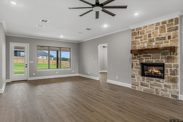 unfurnished living room featuring hardwood / wood-style flooring, a stone fireplace, and crown molding