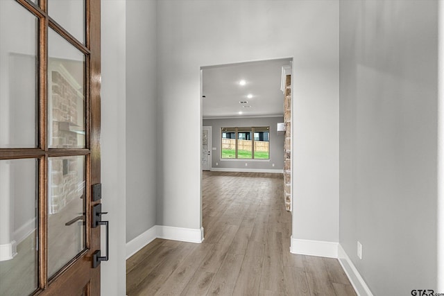 hallway featuring light hardwood / wood-style floors and crown molding