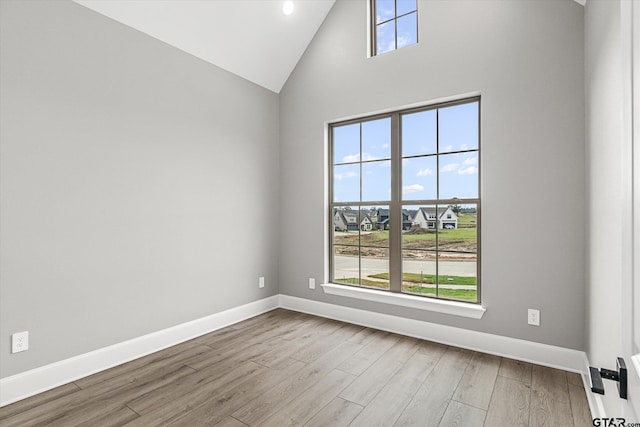 spare room featuring hardwood / wood-style floors and high vaulted ceiling