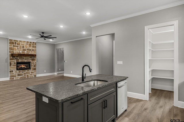 kitchen with dishwasher, a center island with sink, crown molding, sink, and light hardwood / wood-style floors