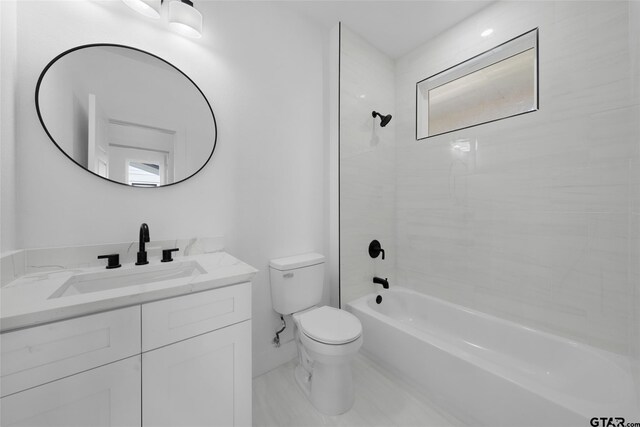 full bathroom with vanity, tiled shower / bath, and toilet