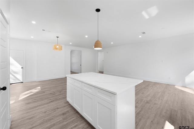 kitchen featuring white cabinetry, light hardwood / wood-style flooring, light stone counters, and decorative light fixtures