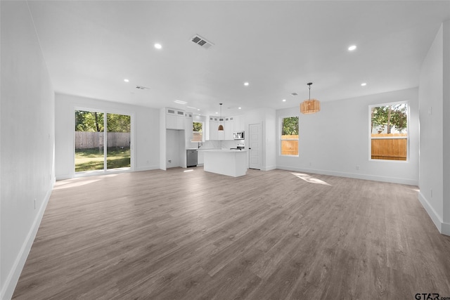 unfurnished living room featuring a wealth of natural light and light hardwood / wood-style flooring