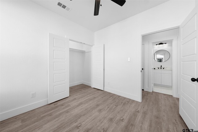 unfurnished bedroom featuring light hardwood / wood-style flooring, ceiling fan, ensuite bath, and a closet