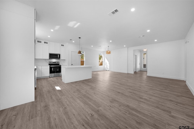 kitchen featuring wood-type flooring, appliances with stainless steel finishes, decorative light fixtures, white cabinets, and a center island