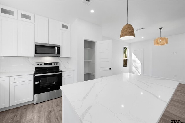 kitchen with light stone counters, stainless steel appliances, light wood-type flooring, pendant lighting, and white cabinets