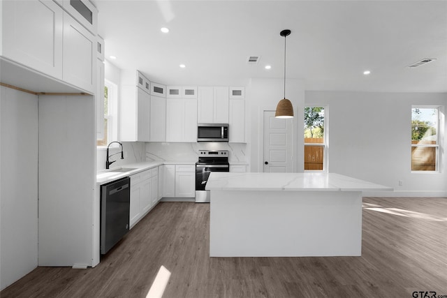 kitchen featuring white cabinets, stainless steel appliances, a kitchen island, and plenty of natural light