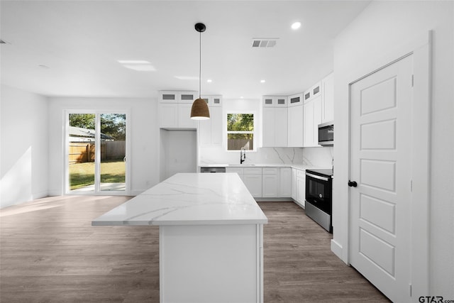 kitchen with white cabinetry, sink, appliances with stainless steel finishes, decorative light fixtures, and a center island