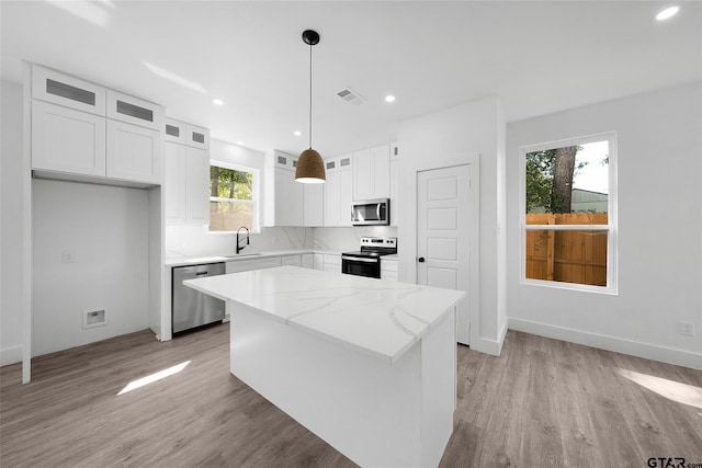 kitchen with white cabinets, stainless steel appliances, a healthy amount of sunlight, and a center island