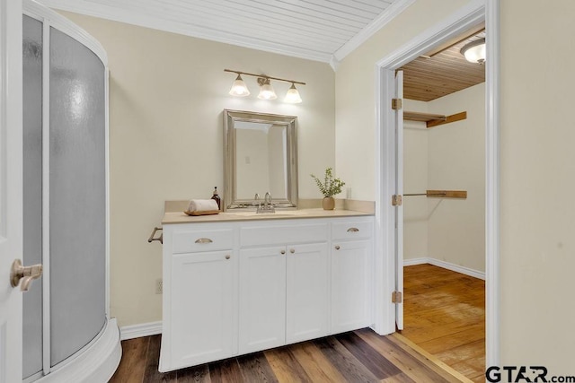 bathroom with a shower stall, wood finished floors, vanity, wooden ceiling, and ornamental molding