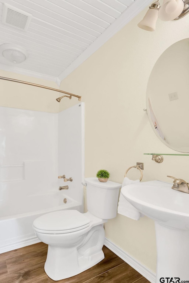 bathroom with toilet, visible vents, baseboards, shower / bath combination, and wood finished floors