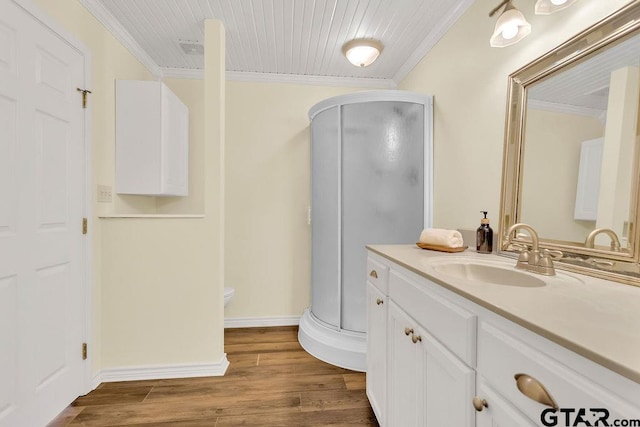 bathroom with a shower stall, crown molding, vanity, and wood finished floors