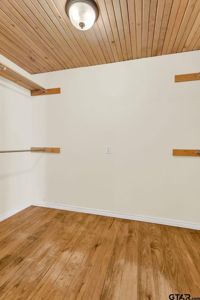 spare room featuring wood finished floors, baseboards, and wooden ceiling