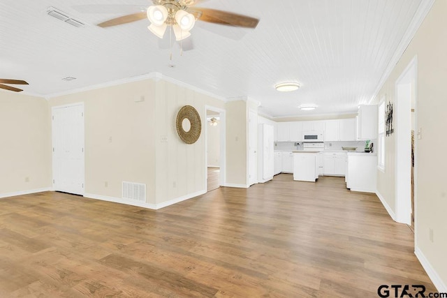 unfurnished living room featuring wood finished floors, a ceiling fan, visible vents, and ornamental molding