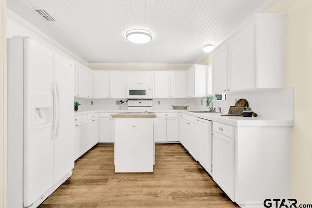 kitchen with a sink, visible vents, white appliances, light countertops, and a kitchen island