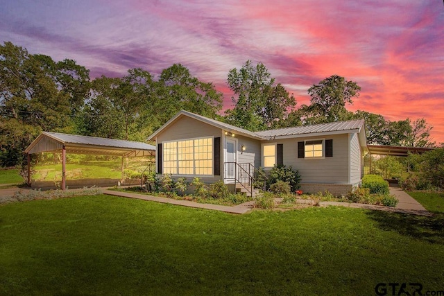 ranch-style home with metal roof, a detached carport, and a front yard