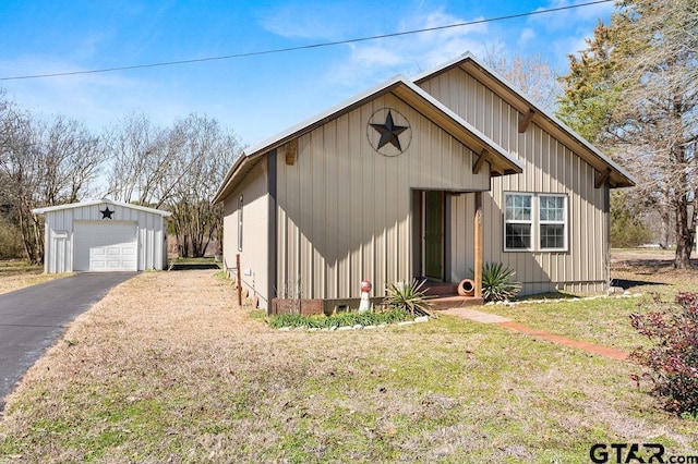 view of front of home with a garage, driveway, an outbuilding, a front lawn, and board and batten siding