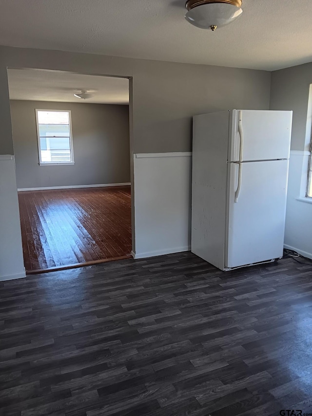 kitchen featuring baseboards, a textured ceiling, dark wood finished floors, and freestanding refrigerator