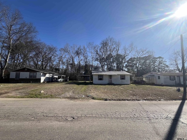 view of front of house with a carport, metal roof, and a front yard