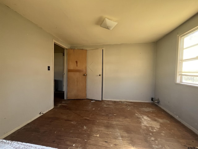 empty room featuring baseboards and hardwood / wood-style flooring