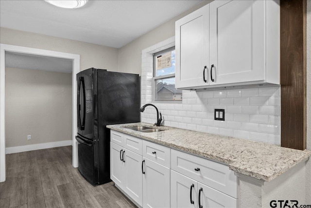 kitchen with dark hardwood / wood-style floors, black refrigerator, white cabinetry, and sink