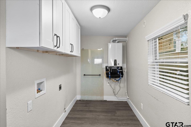 washroom featuring tankless water heater, cabinets, dark hardwood / wood-style flooring, hookup for a washing machine, and a textured ceiling