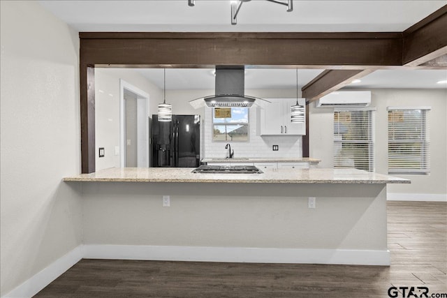 kitchen featuring white cabinetry, black refrigerator with ice dispenser, an AC wall unit, island exhaust hood, and decorative light fixtures