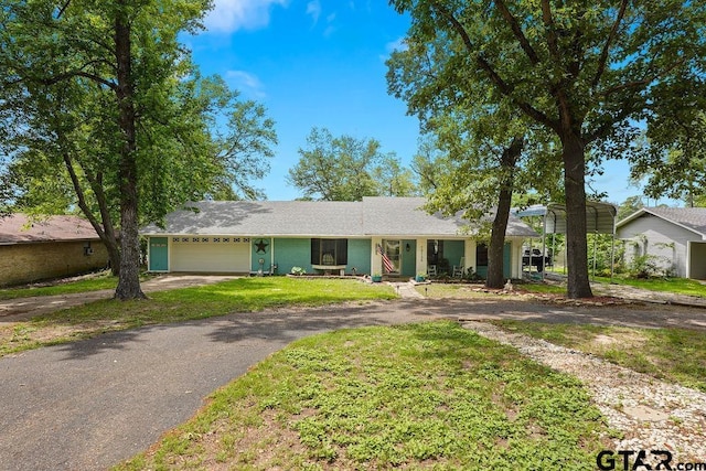 ranch-style home featuring a garage, driveway, a front yard, and a carport