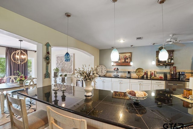 kitchen with decorative light fixtures, visible vents, white cabinets, a notable chandelier, and a breakfast bar