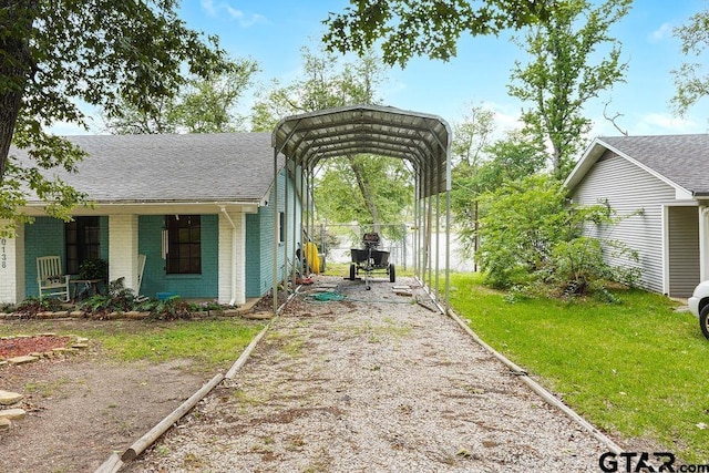view of yard with dirt driveway, fence, and a carport