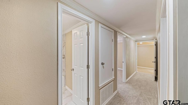 hall with light colored carpet and crown molding