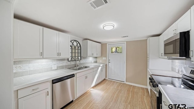 kitchen with white cabinets, sink, light hardwood / wood-style flooring, tasteful backsplash, and stainless steel appliances