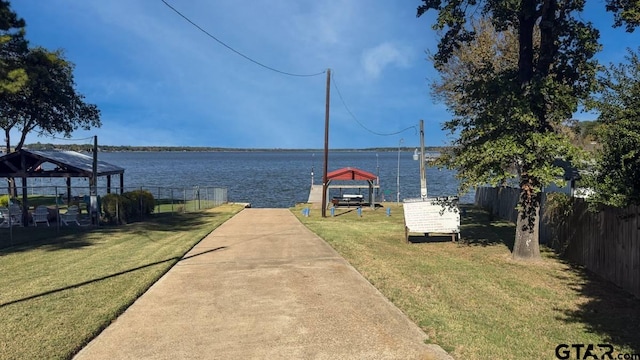 dock area with a gazebo, a water view, and a yard